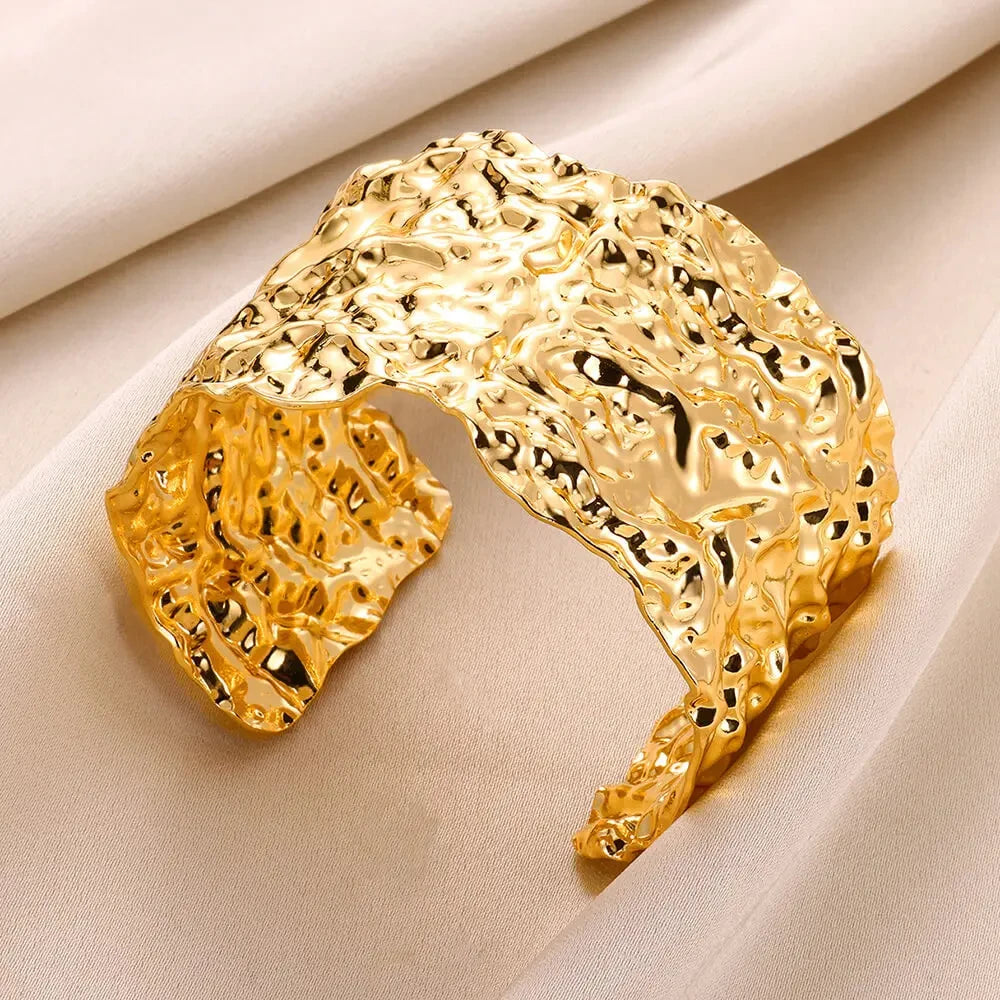 Gold bracelet with textured design on a beige fabric background