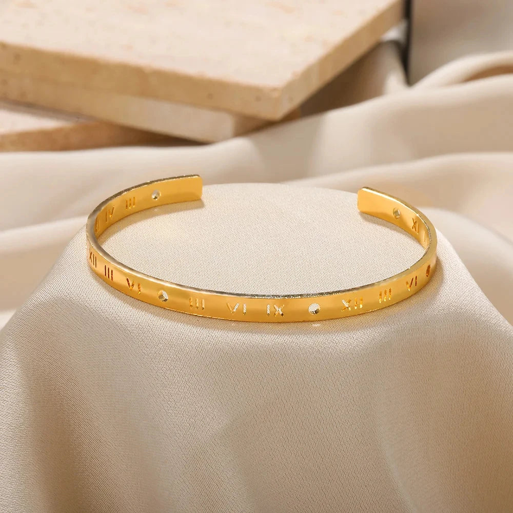 Gold bracelet with engraved symbols on a beige fabric background