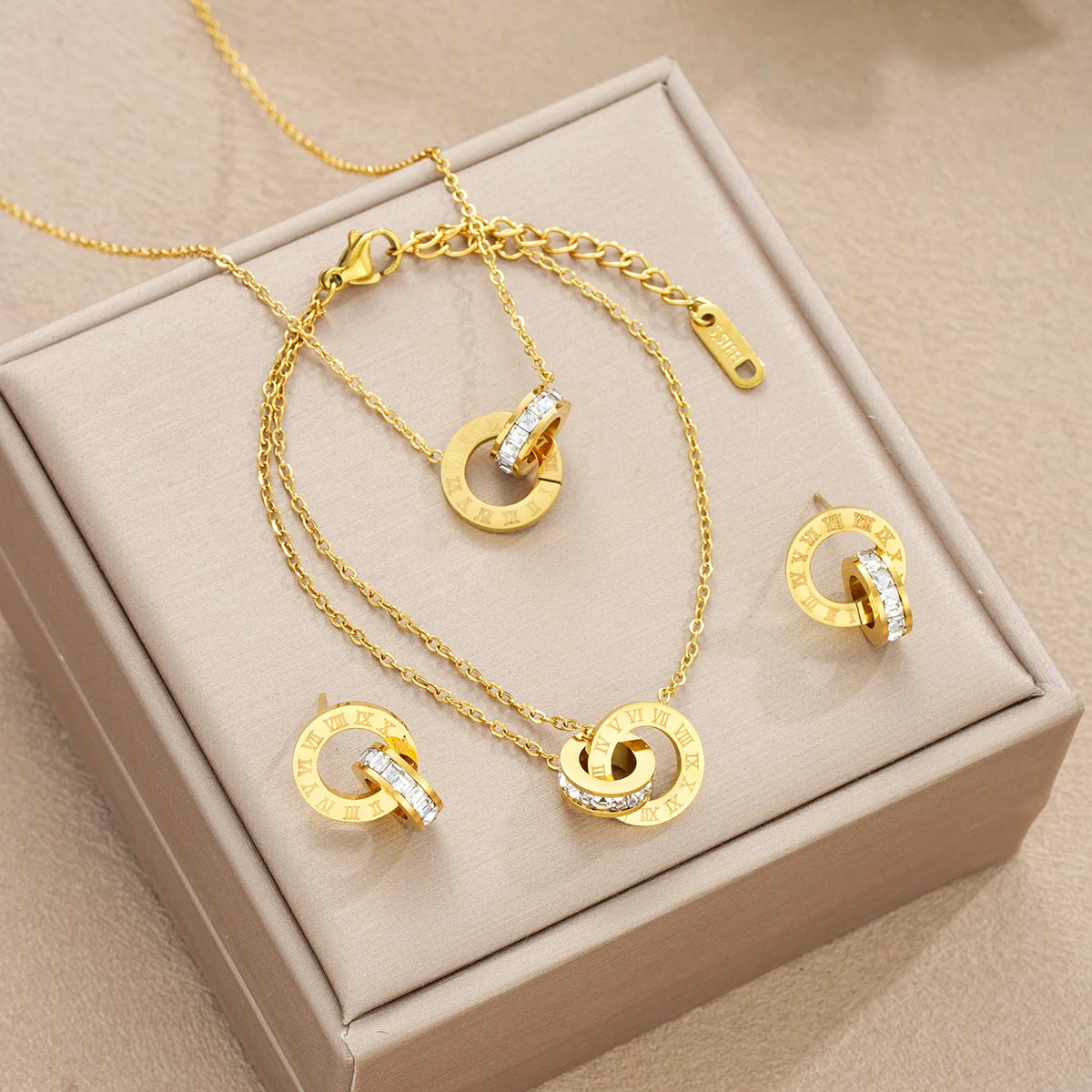 Gold jewelry set with necklace and earrings on a beige box