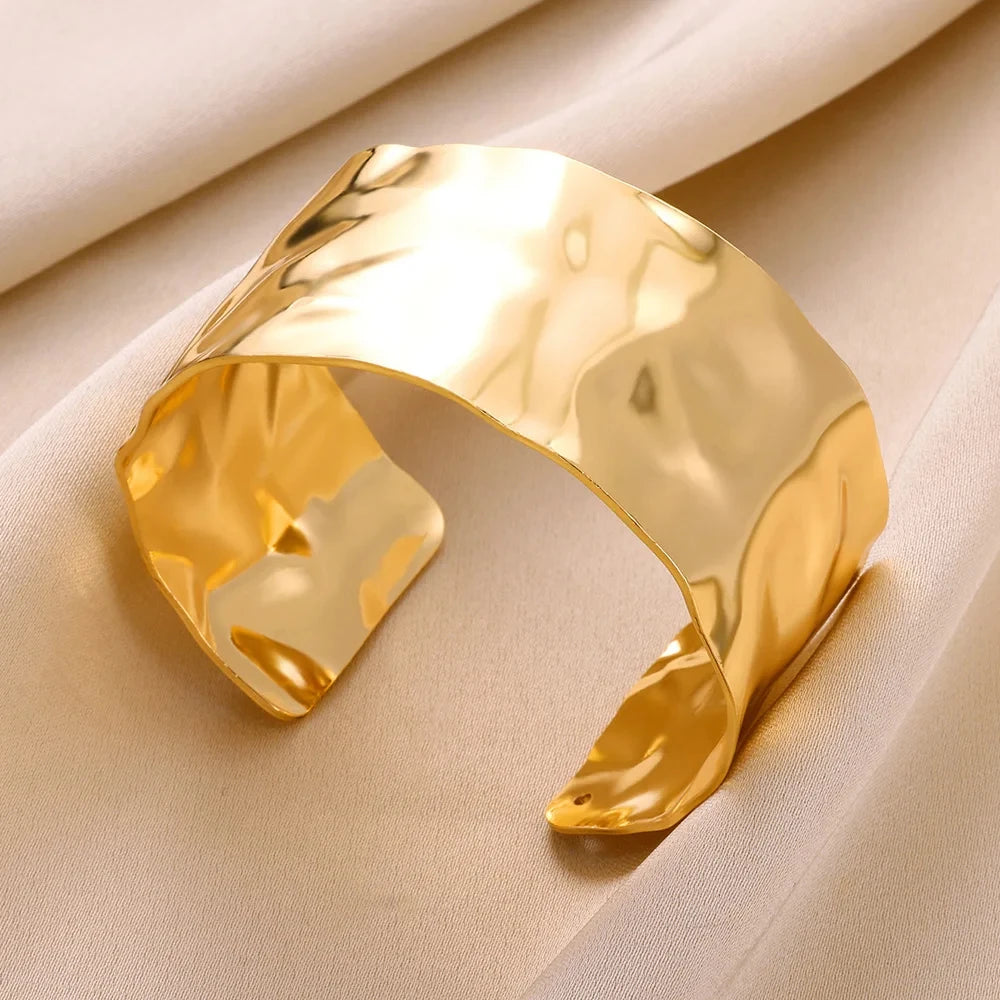 Gold cuff bracelet on a beige fabric background