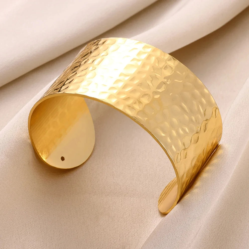 Gold cuff bracelet on a beige fabric background