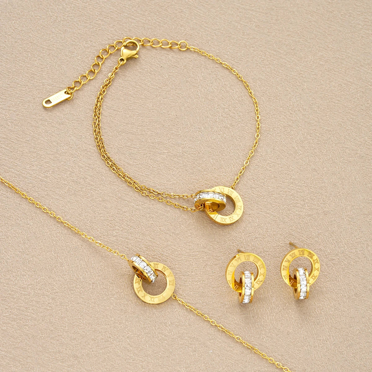 Gold jewelry set with necklace, bracelet, and earrings on a beige background